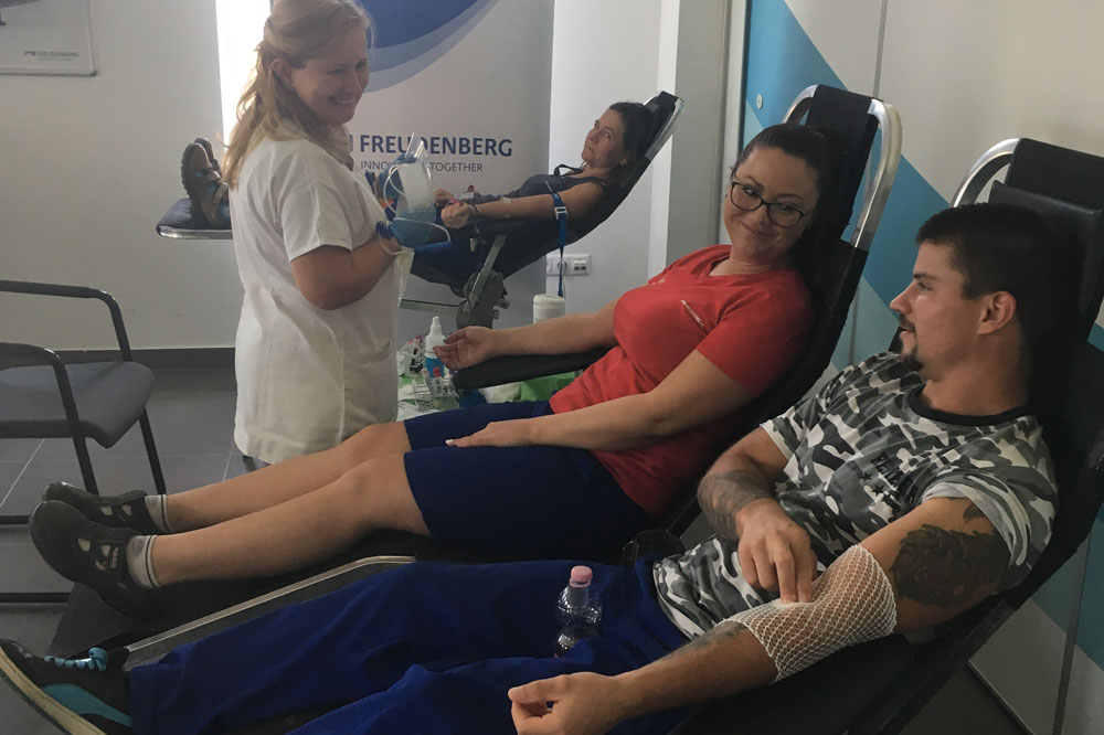 Three Freudenberg Kecskemét employees donate blood and a nurse prepares everything