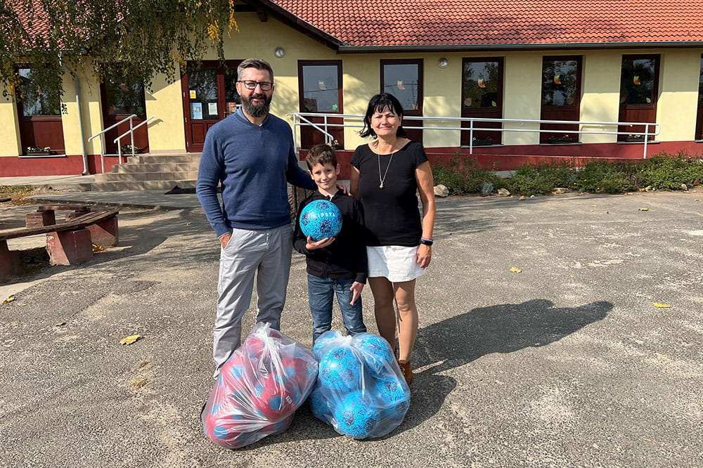 A man, a woman and a child pose with two bags of balls