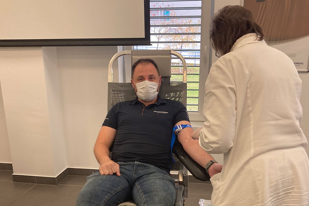Employee with a mask over his mouth gives blood
