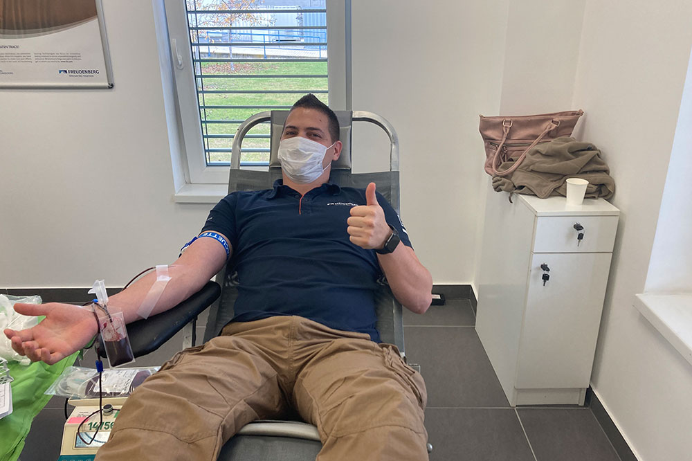 Employee with a mask over his mouth gives blood