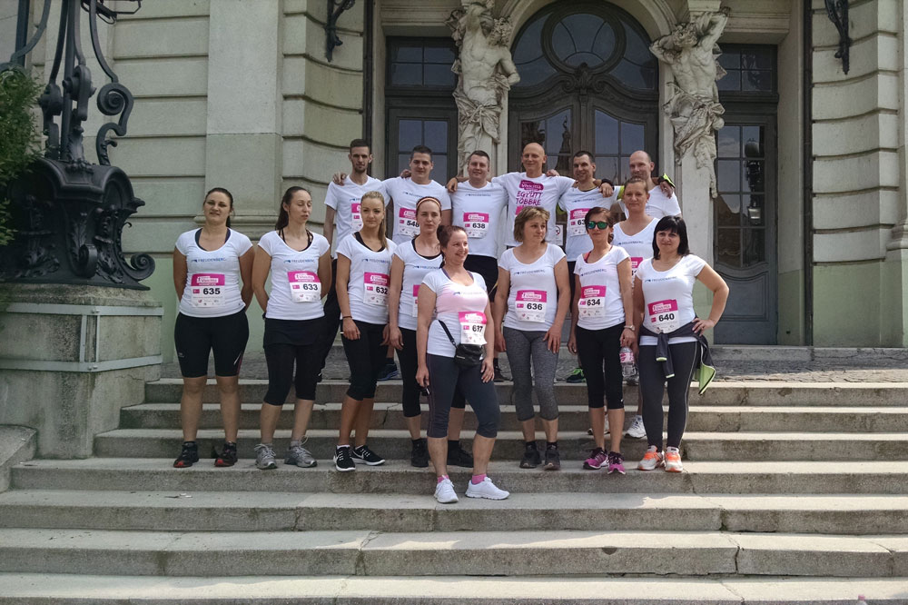 Group photo of Freudenberg Kecskemét employees on the stairs and in front of historic building