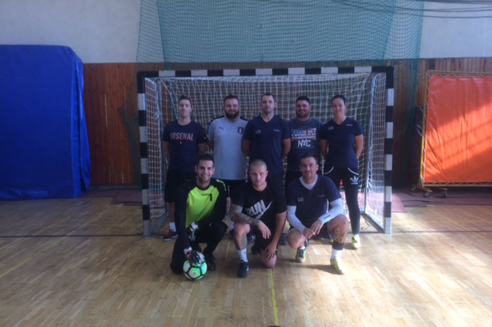 A third team of employees stands in front of the soccer goal, three employees squat on the floor
