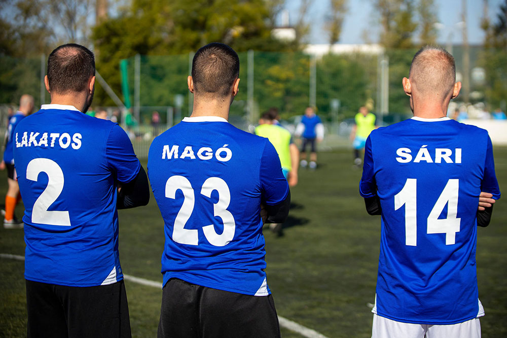 Three soccer players from behind, making the back motif of the jersey in the foreground