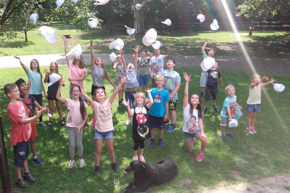 Children throw their Freudenberg caps into the air in the park