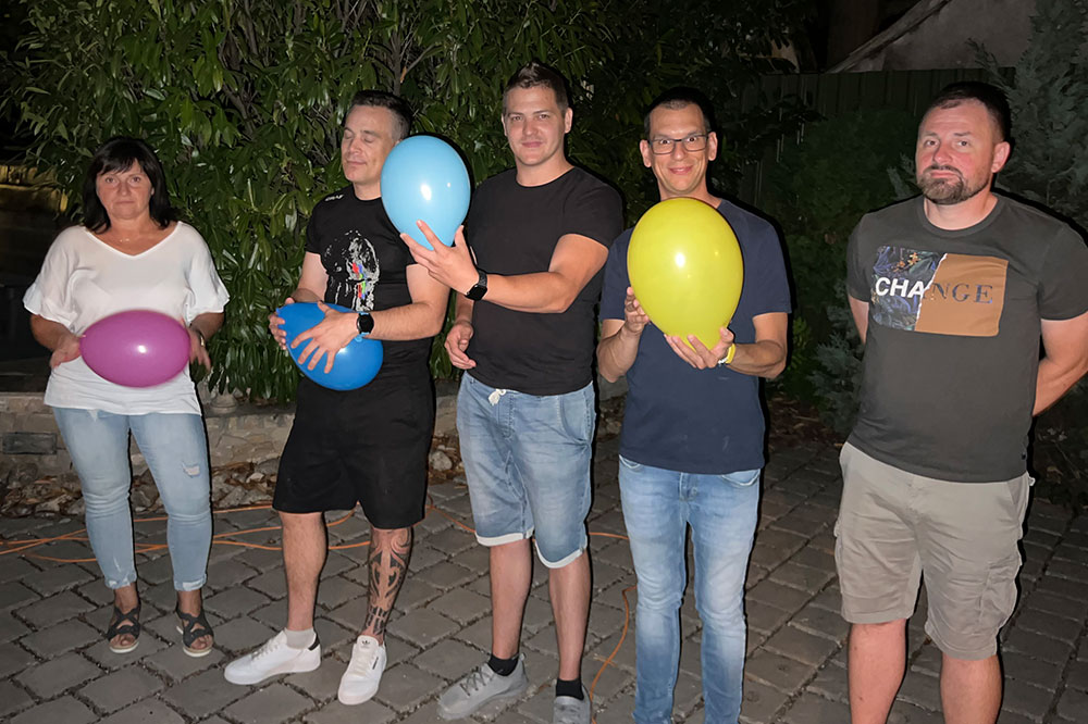 Employees stand together with balloons in hand for a group picture