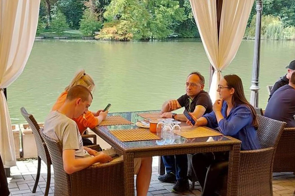 Staff sitting outside at a table by the lake