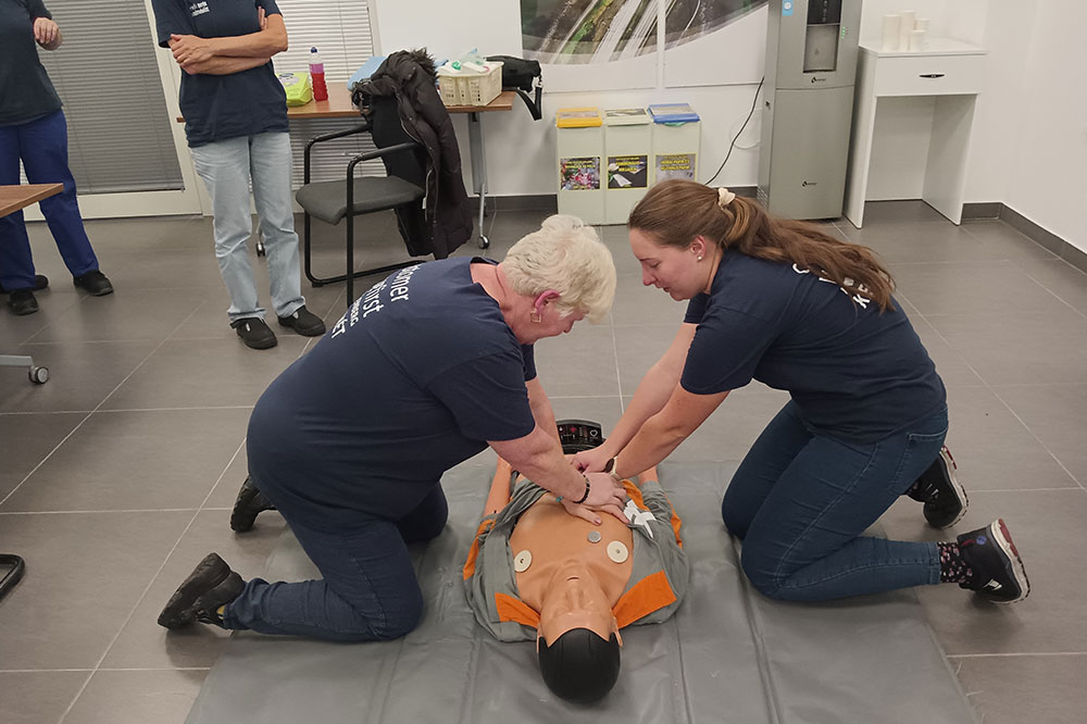 Two employees practising first aid on a training dummy